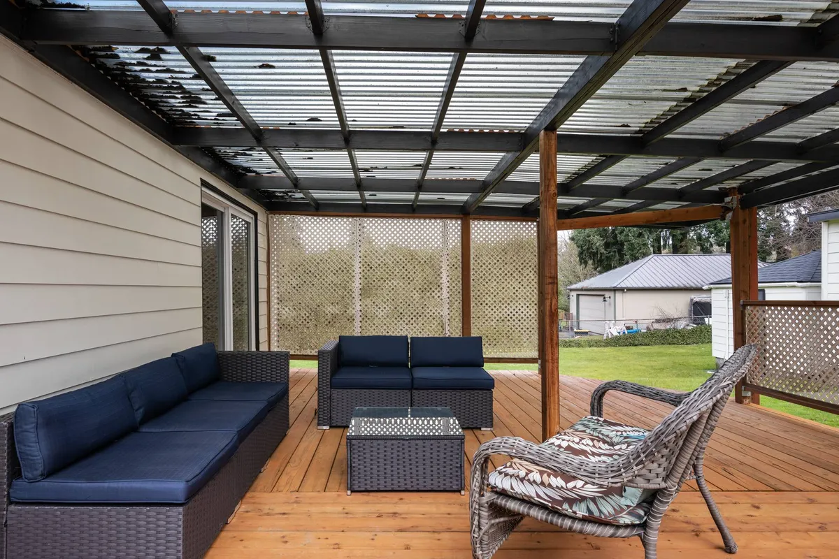 Here, an outdoor seating area is set on a wooden deck, bordered by a decorative lattice privacy screen. The space is designed for socializing or quiet moments, with comfortable seating and tranquil natural views. The area is ideal for both group gatherings and peaceful solitude, enhanced by the sense of privacy provided by the screen.