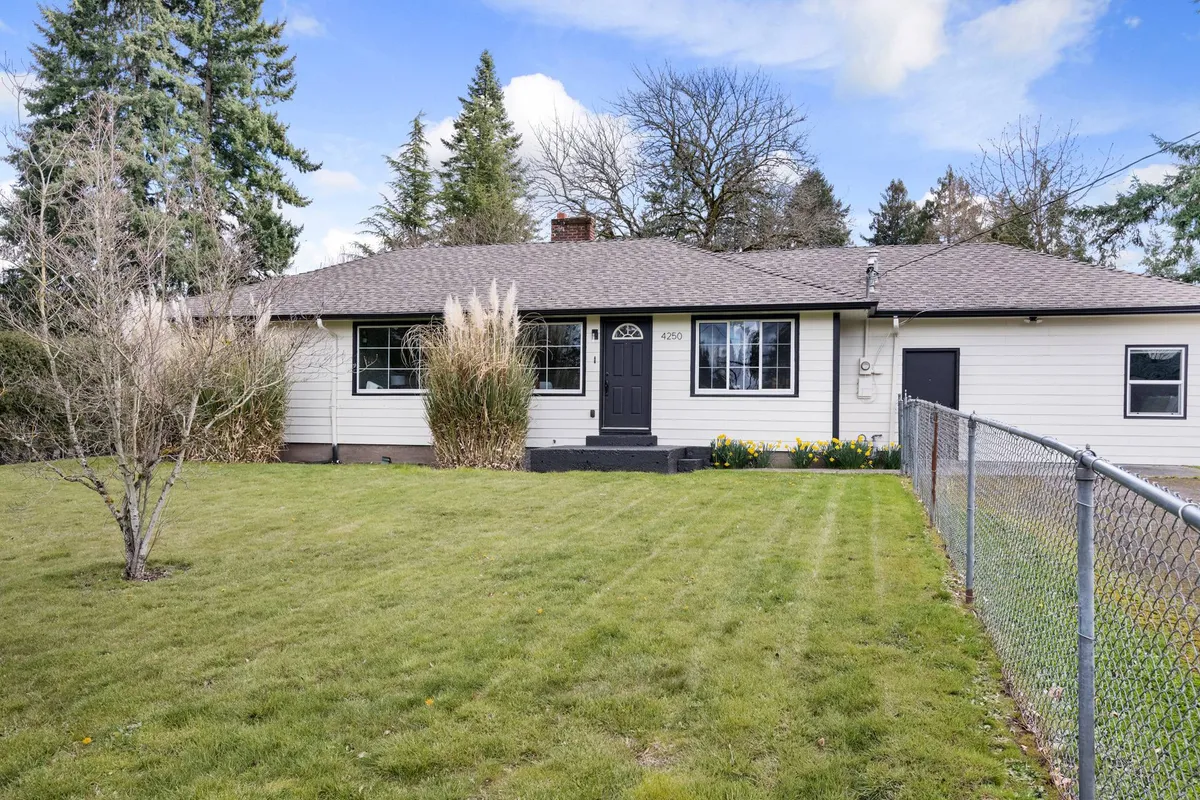 A view of the home's welcoming front entrance, surrounded by well-kept landscaping and a tall privacy fence. The scene suggests an inviting, private yard perfect for outdoor activities and socializing with friends or family.