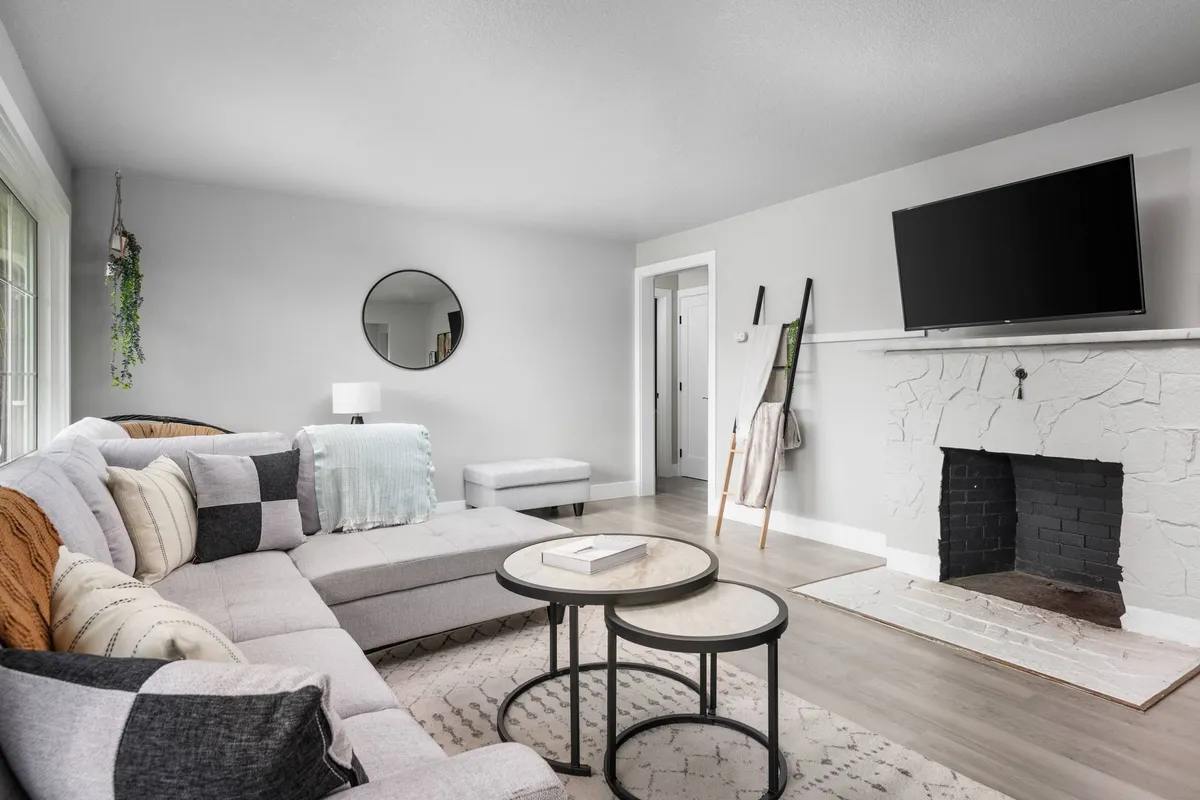 A stylish living room with a sectional sofa, coffee table, fireplace, TV, and decorative mirror. The mood is both comfortable and modern, offering a space for relaxation, team meetings, or watching TV after a long day.
