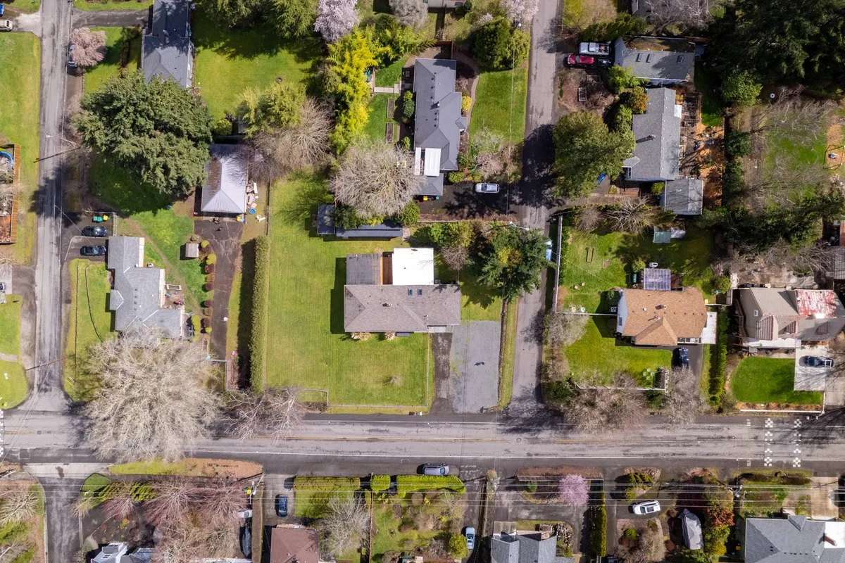 A peaceful neighborhood scene featuring spacious green lawns, a variety of house styles, and tree-lined streets. The environment is calm yet vibrantly residential, suggesting opportunities for outdoor play, local exploration, and community experiences.