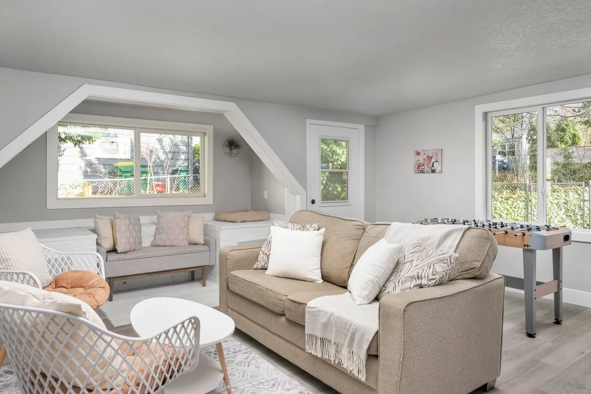 A comfortable living area with a cozy sofa and coffee table set near a window, complemented by a foosball table. The space feels open and inviting, perfect for both relaxing and engaging in games with friends or family.