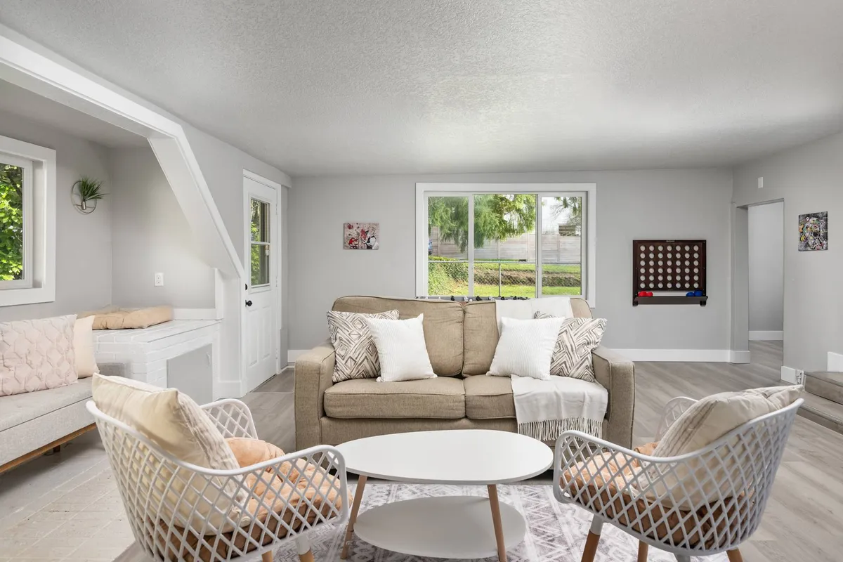 A cozy interior scene with a plush sofa, a coffee table, and expansive windows. The seating area is arranged for both relaxation and socializing, with soft lighting and a welcoming atmosphere.